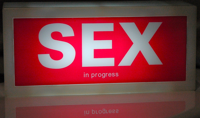 [Image] A lit up red sign reading "Sex in Progress"